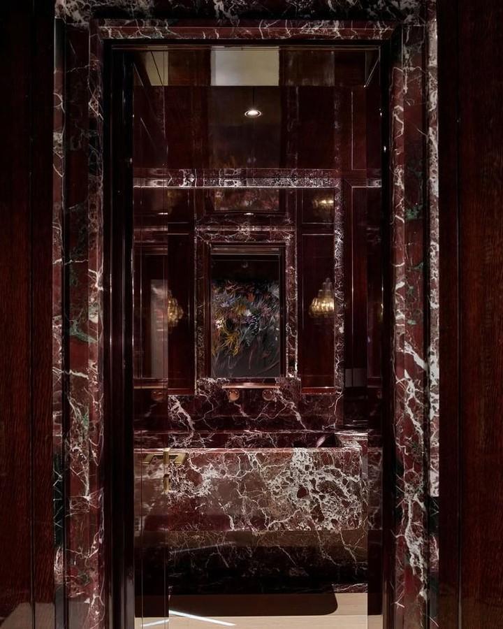 Dark red marble powder room walls and sink from @theobjectcollective_ with white veining and dark wood frame details creating striking red powder room ideas.
