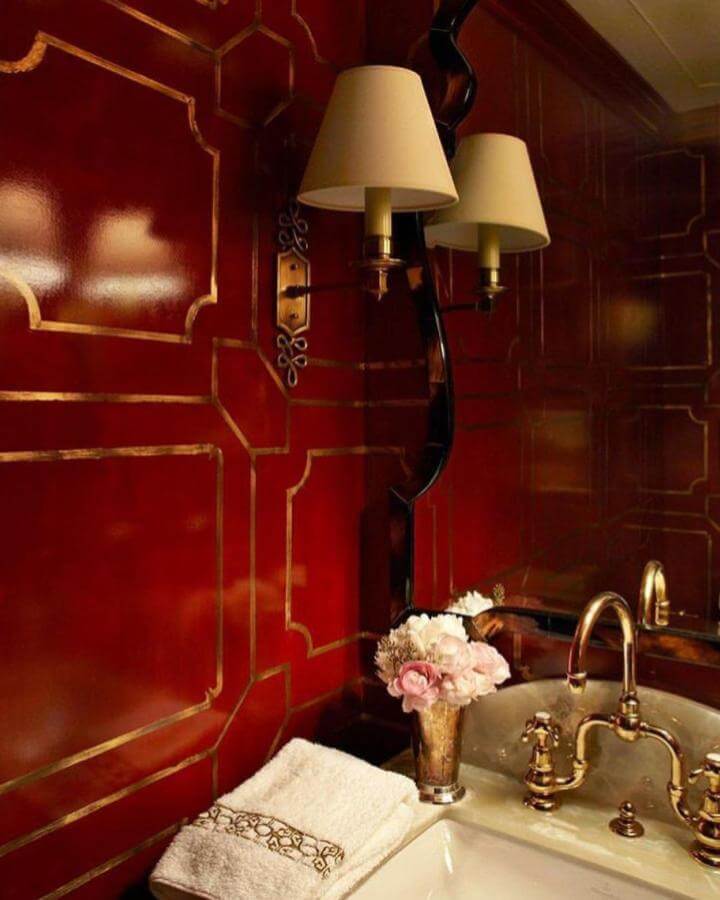 Glossy red and gold detailed powder room with brass fixtures and vintage sconce from @dallasbonds. Elegant and dramatic red powder room ideas.