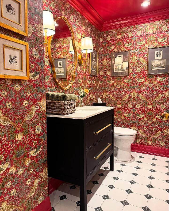 Red floral wallpaper and black vanity in a red powder room from @luxurious.liveable.interiors with vintage-inspired decor and brass accents.