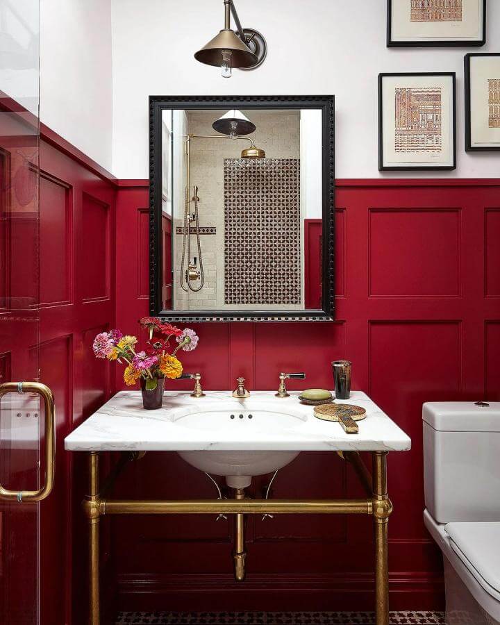Red wainscoting and brass pipe sink in powder room from @suzannetuckerhome. Warm and inviting red powder room ideas.