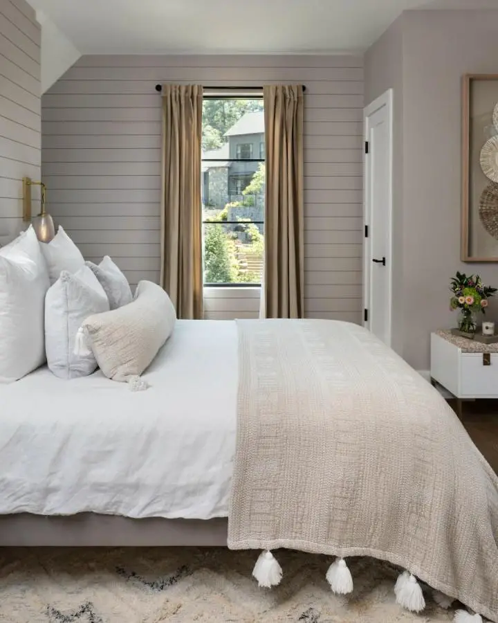Soft gray shiplap bedroom from @lawlerdesign featuring white linens and beige curtains for a relaxing bedroom sanctuary.