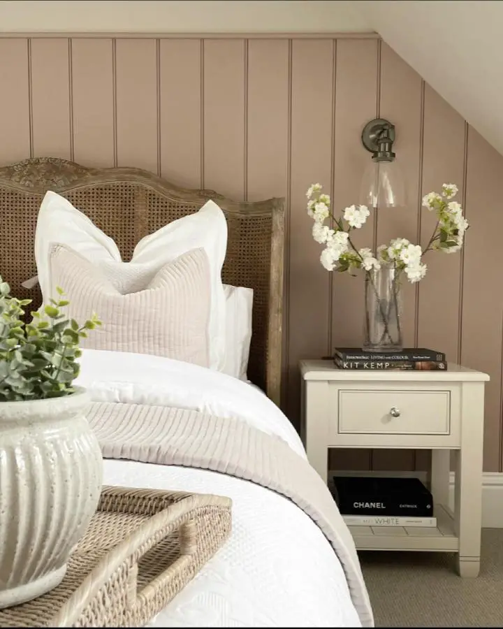 Curved wicker headboard from @cuddledown_uk. Natural texture against beige paneled wall with white bedding.