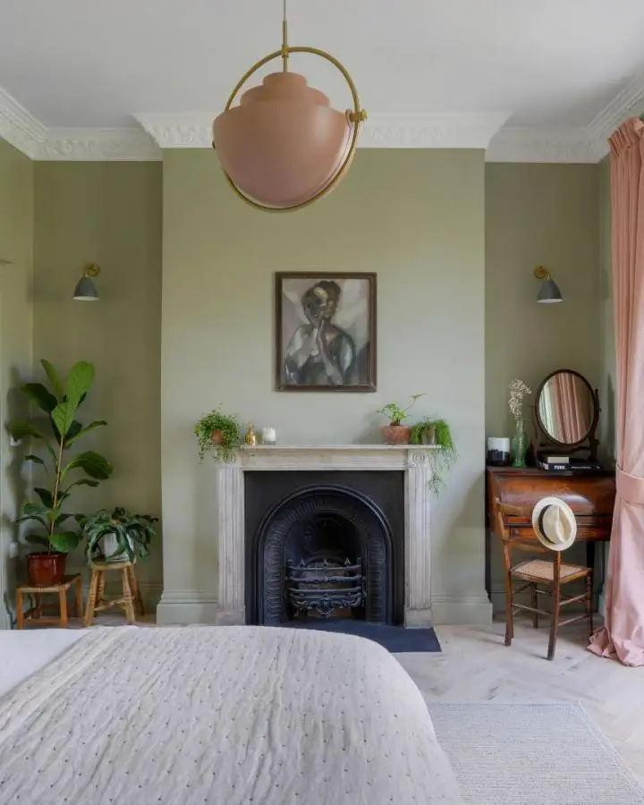 Sage green painted bedroom from @kbbmagazine. Victorian fireplace with wooden desk and brass lighting fixtures.