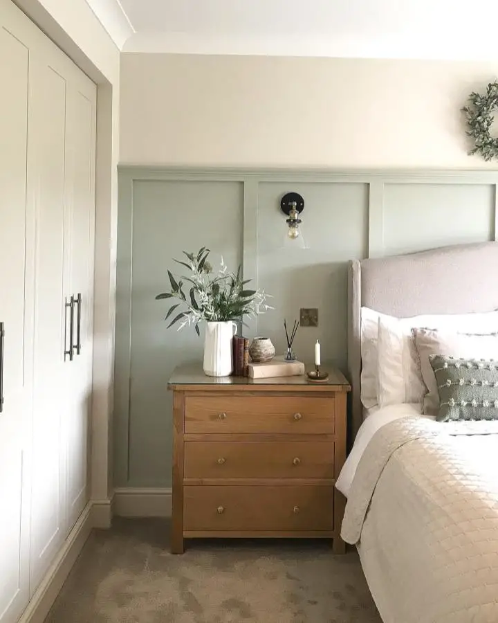 Soft sage paneled bedroom from @thegrange_renovationproject. Natural wood nightstand against painted wall treatment.