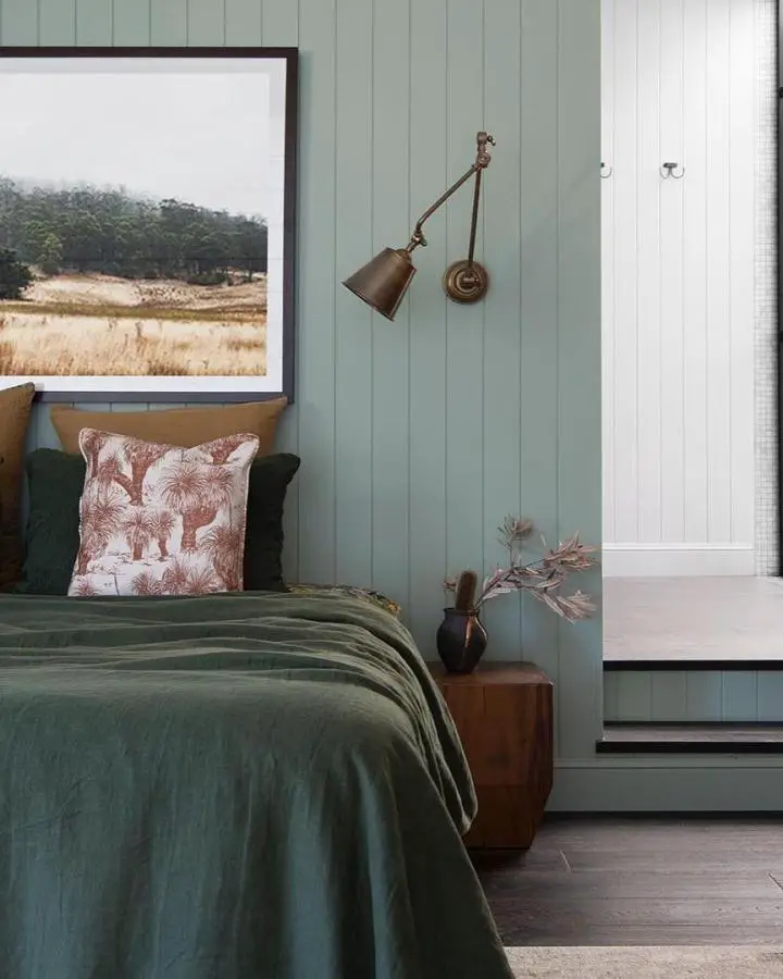 Sage green paneled bedroom from @pigletinbed. Brass swing arm wall light and matching bedding create cohesive style.