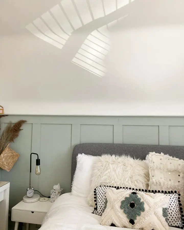 Soft sage paneled bedroom wall from @the.felly.chalet. White bedding and natural textures complete the look.