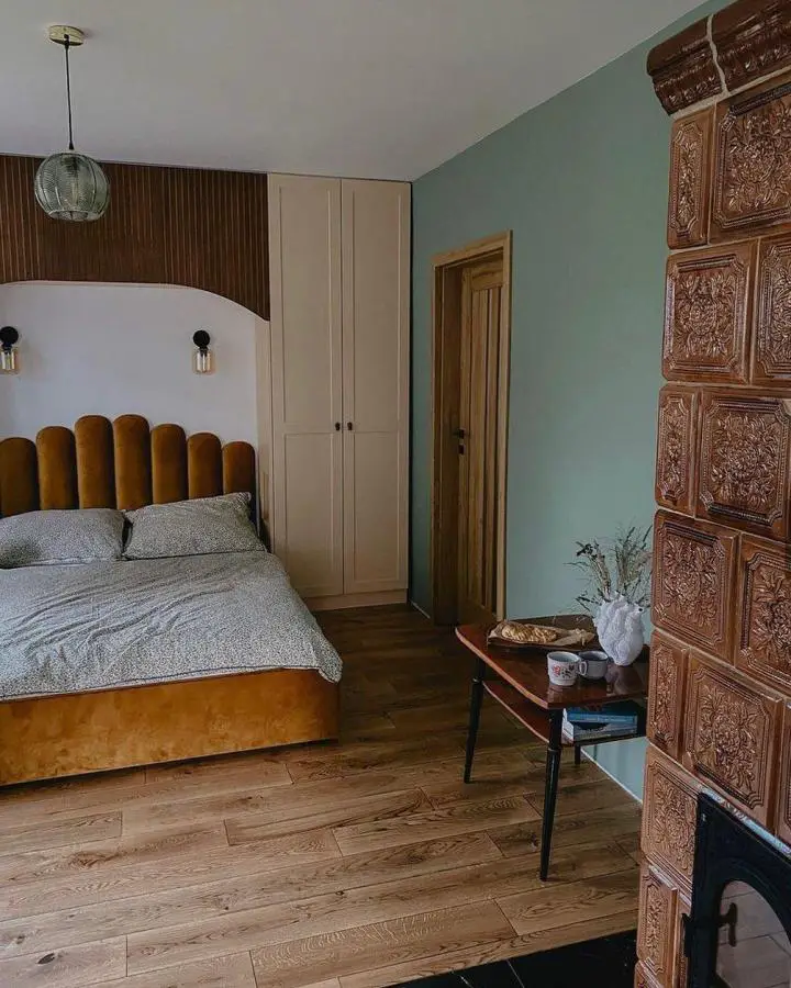 Cozy sage green bedroom from @klechdy_z_ganku. Features mustard velvet headboard and carved wooden accent wall.