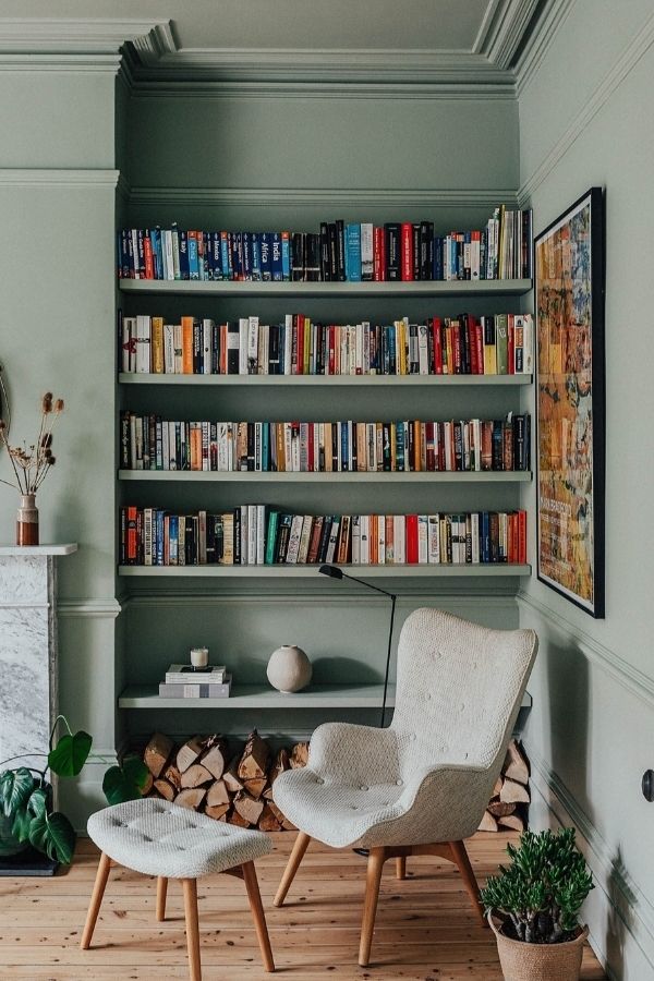 Sage green living room with colorful bookshelves, inspiring sage green living room ideas.