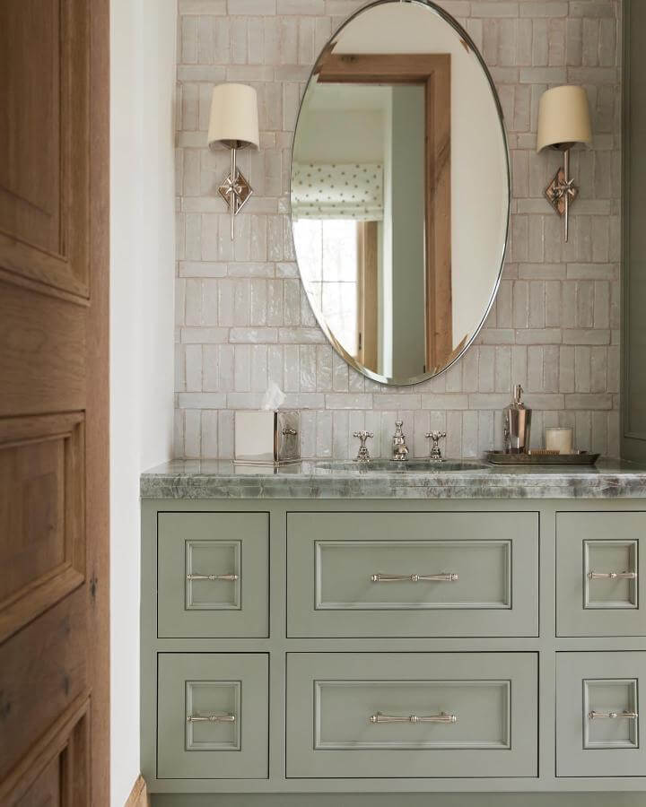 sage green painted vanity with marble countertop in powder room by @nicolegerulat elegant cabinet design and tile backsplash