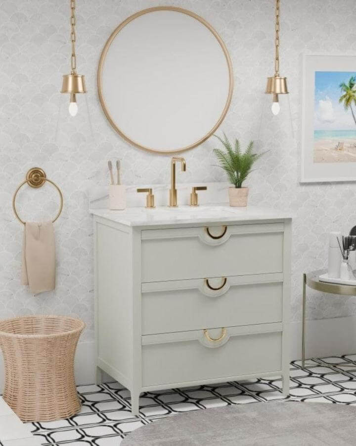 Sage green vanity with brass fixtures and black white patterned tile floor in powder room from @oasistile. Soft green cabinetry with warm metal accents.