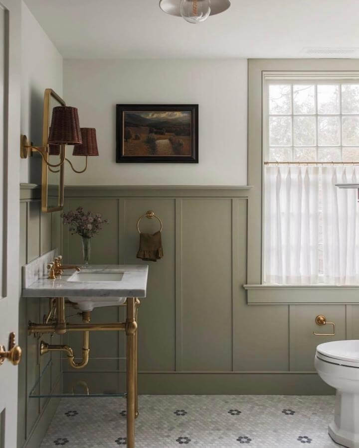 sage green paneled powder room with brass fixtures and floral tile floor from @lygiaharkins_interiors. Soft natural light brightens the serene space