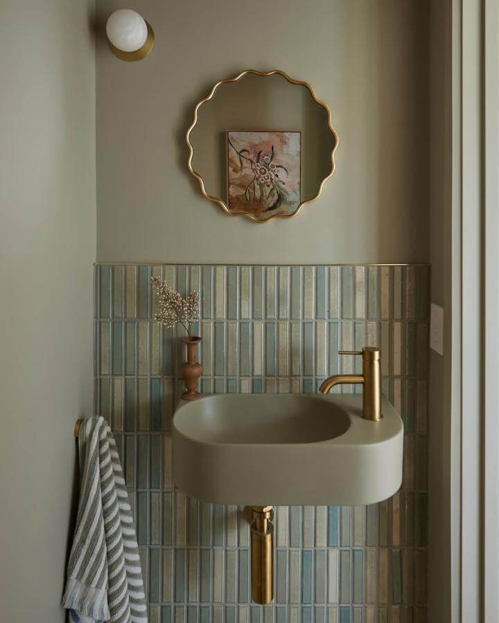 Sage green powder room ideas with sculptural gold mirror and matte basin by @carpathian_design soft and elegant style