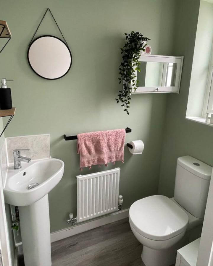 sage green walls with pink towel and black accents in a small powder room from @once.upon.an.alnwick simple and soothing design with natural light