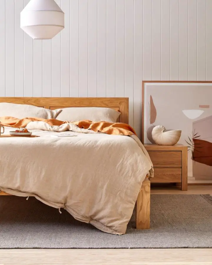 Warm oak bedroom furniture from @icon_by_design. Natural wood frames complement neutral linens and white paneled walls.