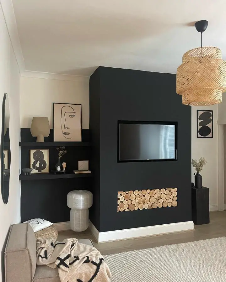 Dark green accent wall living room from @renov8teen. Natural wood log display and woven pendant lighting.