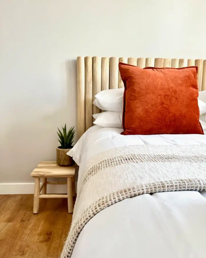 Natural wood slat headboard from @neverfullyfinished. Burnt orange pillow adds warmth to neutral bedding.