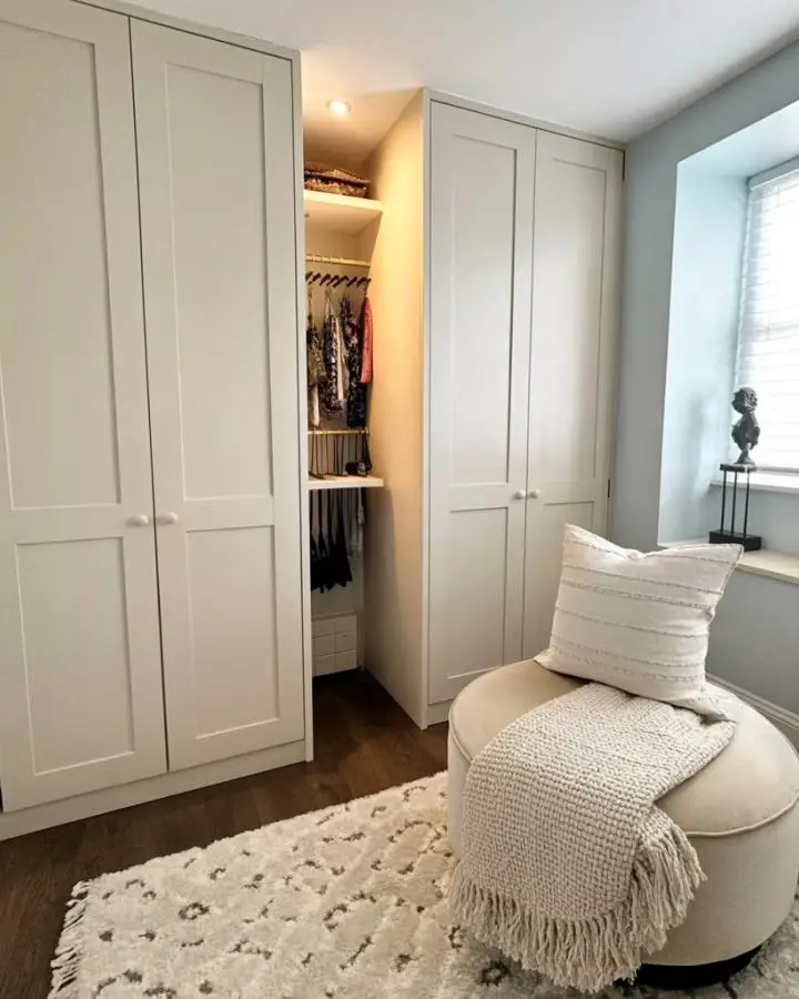 White shaker cabinet doors concealing organized closet space with LED lighting and hanging clothes visible inside.