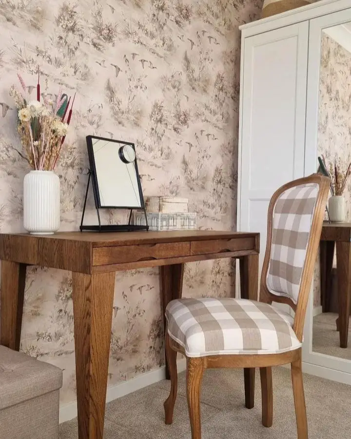 Toile wallpapered vanity corner from @salliekinginteriors. Wooden desk with gingham upholstered chair and neutral decor accessories.