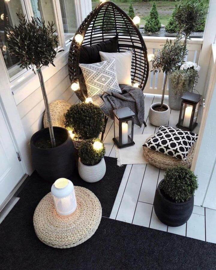 Dark rattan egg chair with string lights and black white accents from @shantevega45. Inviting small patio ideas with cozy lighting and plants.