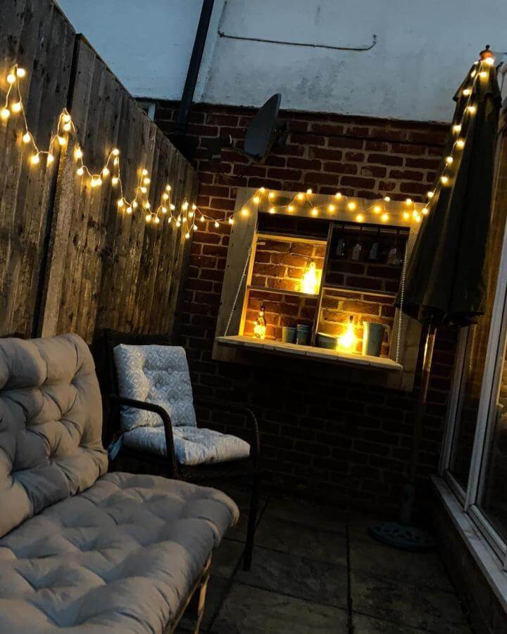 Soft warm string lights and cushioned patio furniture from @_millymolly68. Intimate brick wall nook with cozy seating and ambient lighting.