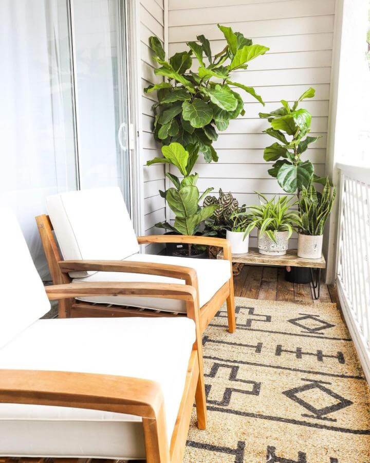 Light wood and white cushion chairs on a patterned natural fiber rug with green potted plants on a small outdoor balcony by @overstock creating a fresh cozy vibe.