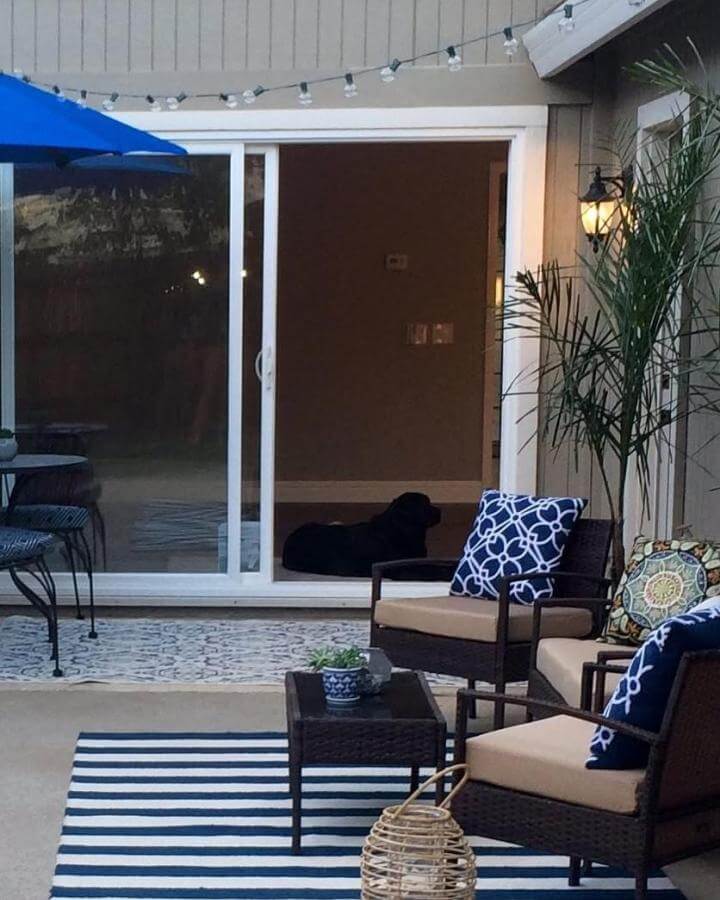 Navy patterned cushions with wicker furniture on a small patio by @outdoorspacedesigns. Cozy inviting outdoor seating space.