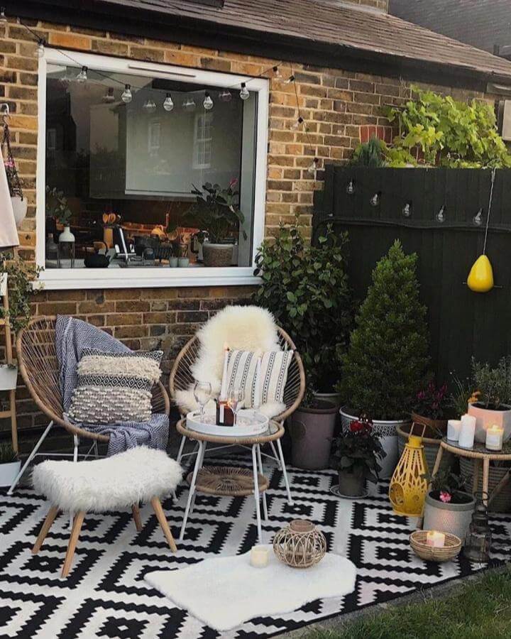 Natural rattan chairs with soft pillows on black and white geometric rug small patio ideas by @myslice_of_heaven with candles and plants creating cozy vibe.