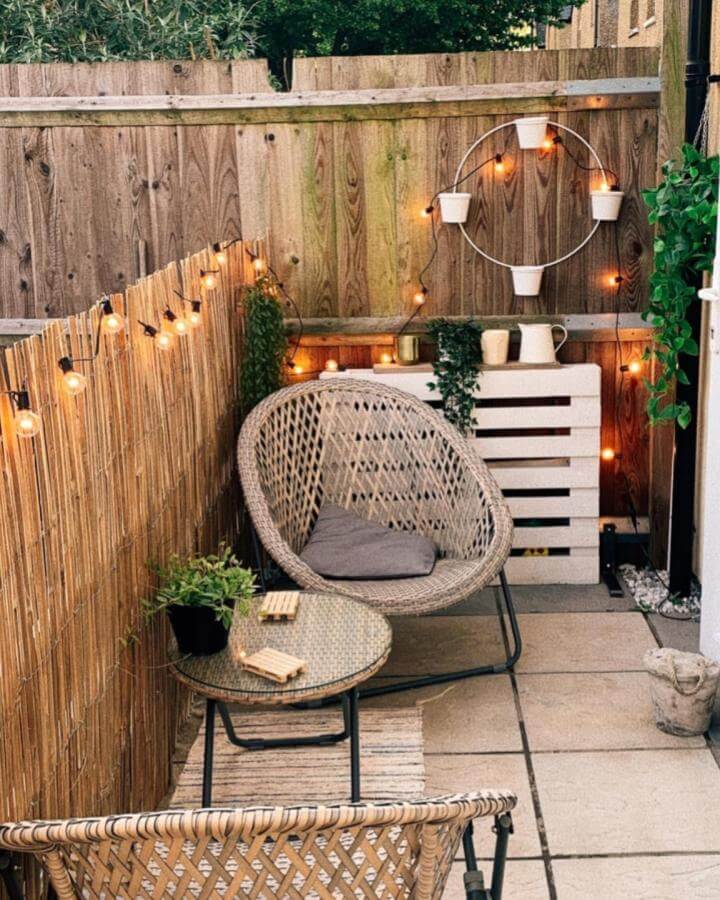 Natural rattan chairs and glass table on a tiny outdoor patio with string lights and plants by @hannah.athome create a charming small space retreat