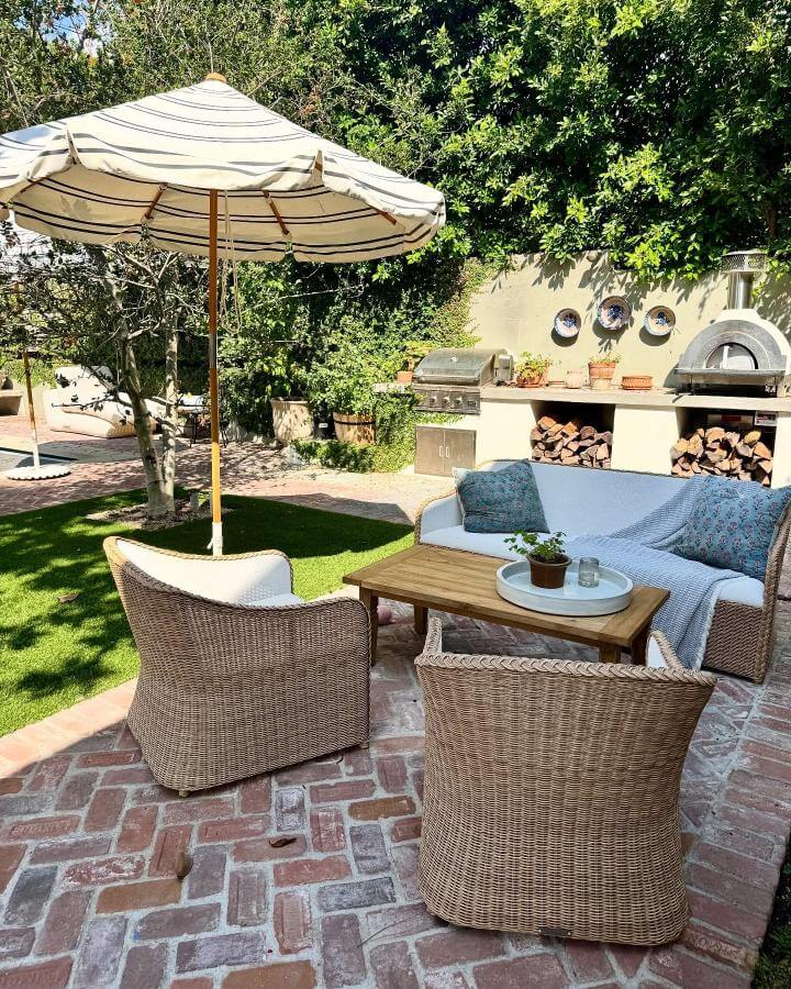 Natural wicker patio furniture with soft blue cushions and striped umbrella from @teryldesigns Small patio ideas with cozy outdoor setup.