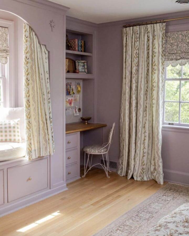 Soft lavender painted bedroom nook with built-in desk and patterned curtains from @dominiepepino warmly styled with natural wood and light textiles.