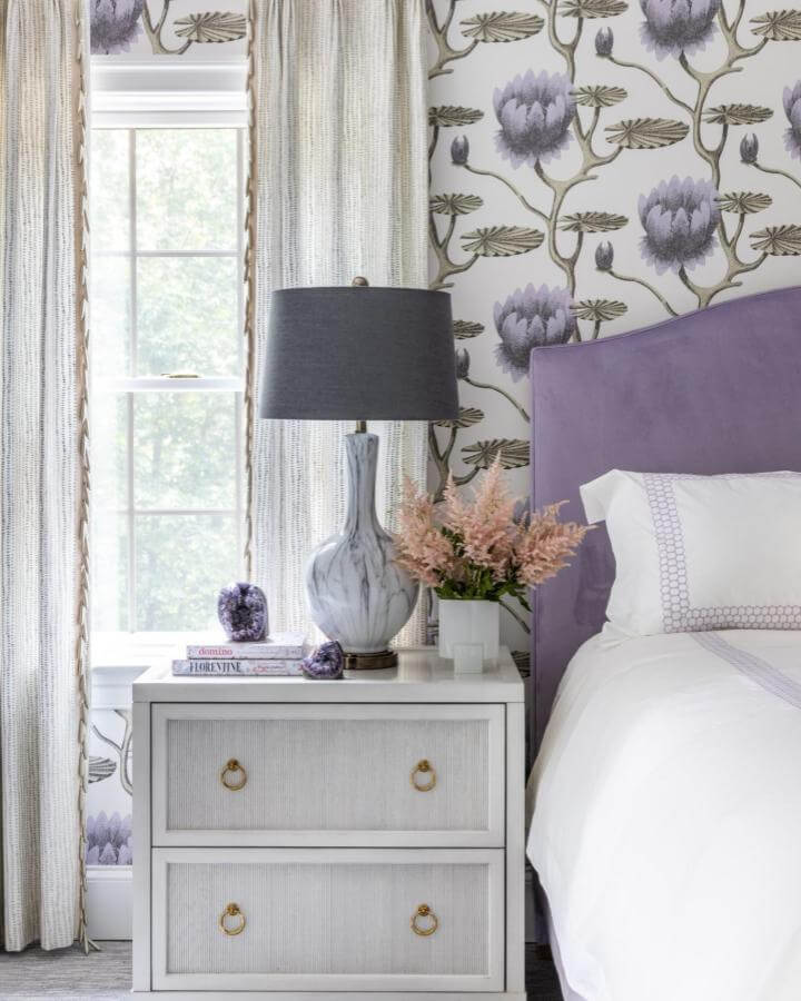 Soft lavender upholstered headboard and floral wallpaper from @erikabonnellinteriors showcasing a serene and elegant bedroom corner.