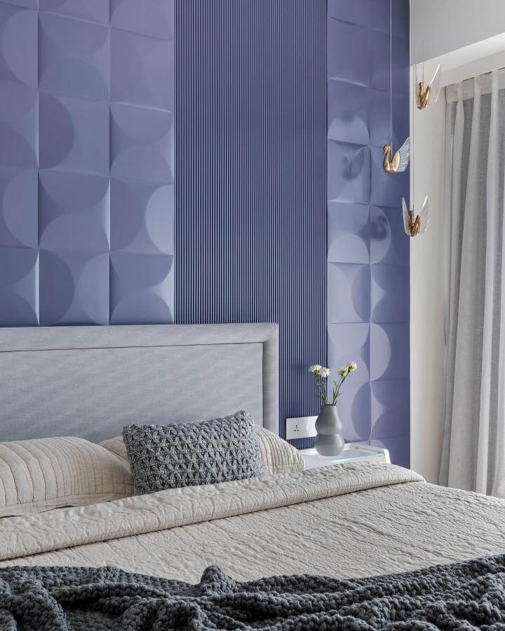 Soft lavender textured wall bedroom by @tanujaandassociates with gray knit pillows and brass bird pendant lights creating a cozy ambiance