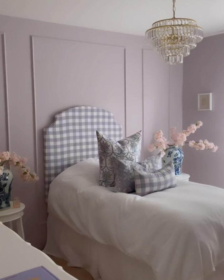 Soft lavender bedroom ideas featuring a gingham upholstered headboard with floral pillows and pink blossoms from @emilyadamsondesigns.