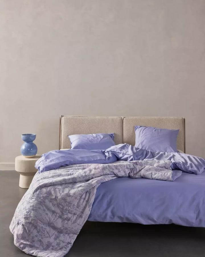 Soft lavender cotton bedding with floral print and beige headboard from @essenzahome. Cozy yet modern bedroom setup.