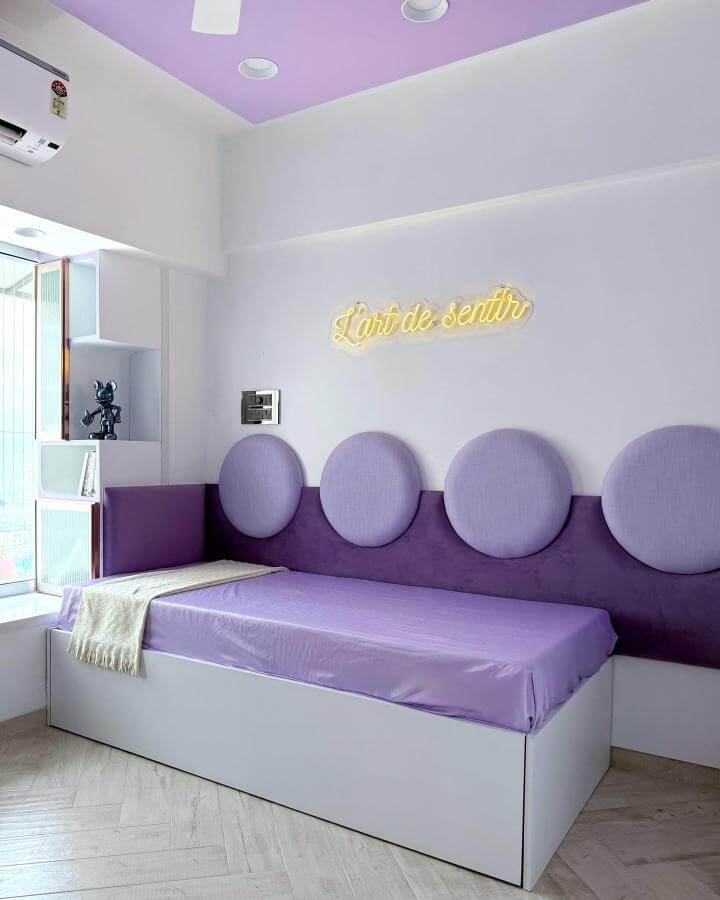 Soft lavender bedroom ideas with circular lavender cushions and neon sign from @kahaanidesignstudio in a compact modern bedroom.