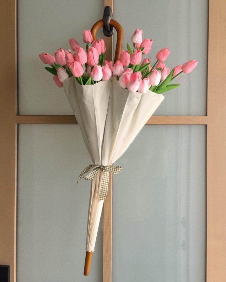 Pink tulip bouquet arranged inside a cream umbrella with gingham ribbon from @rebekahmarsden spring crafts for adults floral display.