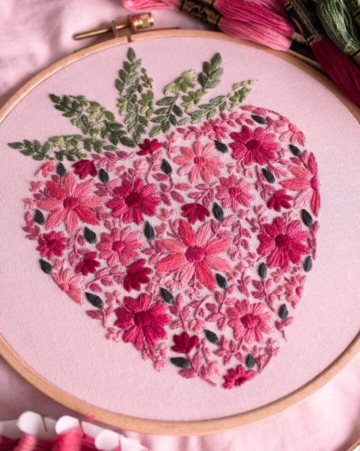 Pink and green floral embroidery in a strawberry shape on blush fabric from @byalyploof spring crafts for adults delicate stitching details.