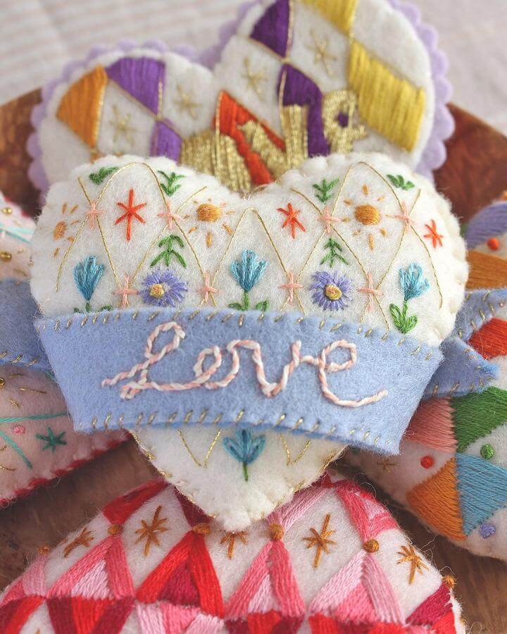 White felt heart embroidered with pastel flowers and the word Love on a blue felt band by @sewyeah spring crafts for adults.
