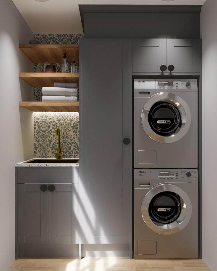 Gray cabinetry stacked washer dryer laundry rooms from @modulrkitchen. Compact space with wooden shelves and patterned backsplash.
