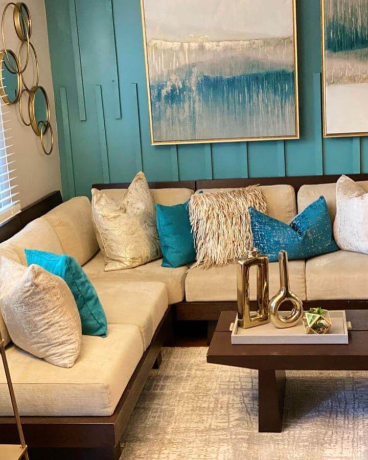 Teal paneled accent wall and beige sofa setup from @mariejonesinteriors with gold accents and textured cushions.