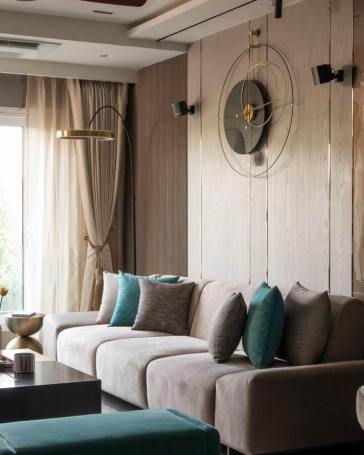 Teal velvet cushions and ottoman with beige sofa and gold accents by @mn_architecture.interiors in a cozy modern living room setting.