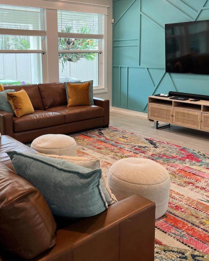 Teal geometric accent wall with brown leather sofas and colorful rug from @modernfloridahome cozy modern living room elements.