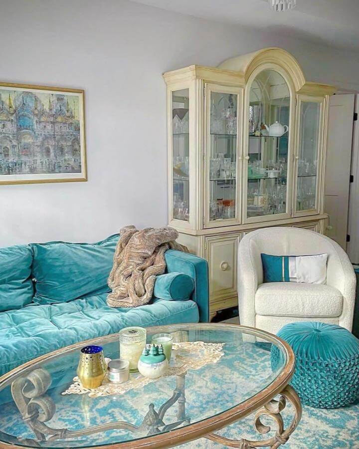 Velvet teal sofa and pouf with cream armchair in cozy living room by @lyndsnoelle showing textured and classic home decor.