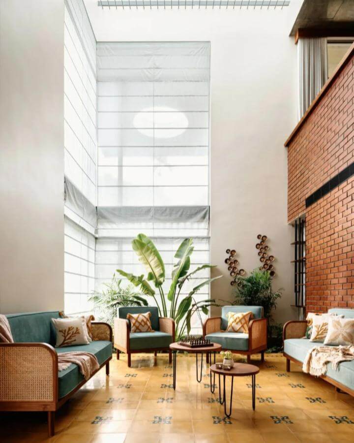 Teal velvet rattan seating from @mudbricks_architects in a sunlit airy room with tropical plants and patterned yellow tiles.