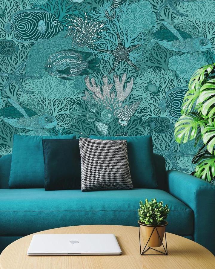 Teal ocean-themed wallpaper and matching couch from @ulrikajarldesign. Underwater coral and fish design for teal living room ideas.