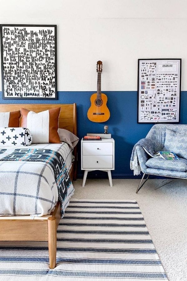 A chic, blue-themed bedroom featuring guitars on the wall.