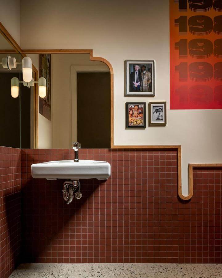Terracotta tiled bathroom walls with unique wooden trim and vintage framed photos by @conradbrownphoto bright and warm design.