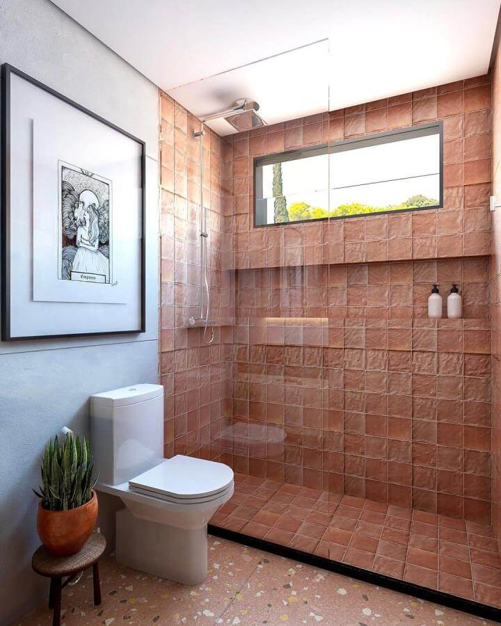 Terracotta tile shower with natural light from @raquelsalesarquitetura featuring warm terracotta bathroom ideas and cozy rustic charm.