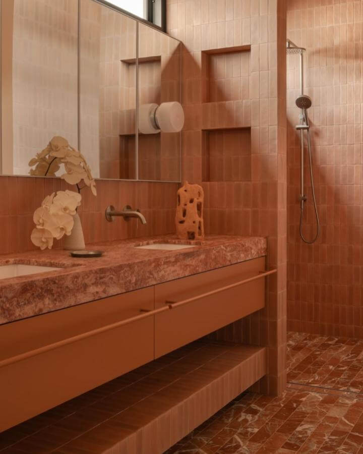 Terracotta tiled bathroom with marble-look countertop and integrated cabinetry designed by @dionrobeson. Warm, earthy, modern style.
