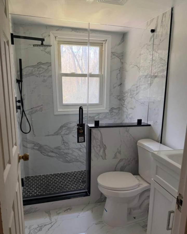 White marble-look tiles bathroom with black shower frame and hexagon floor tiles by @lifeateightysix brightening a compact bathroom space.